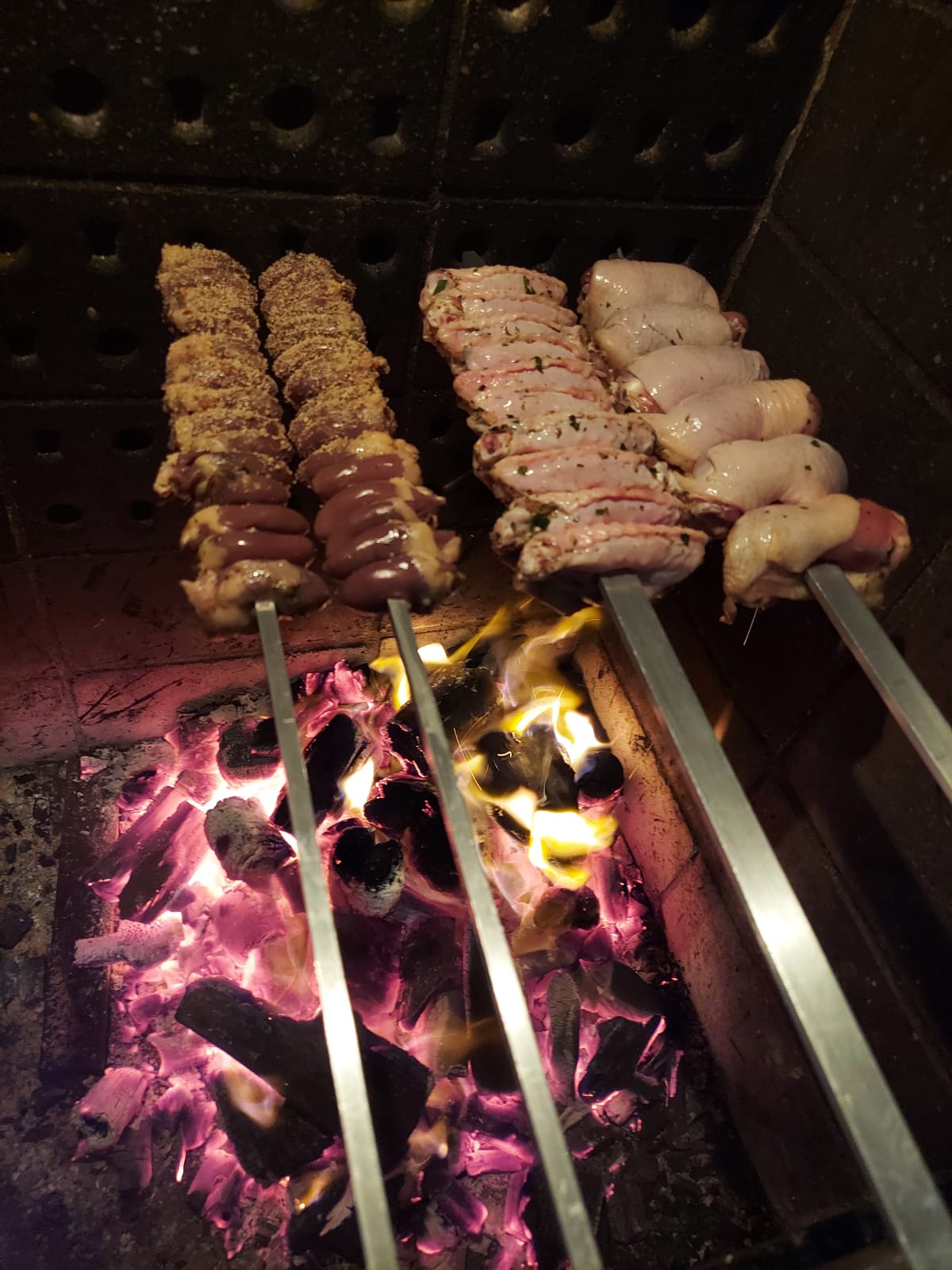 Espetinhos sendo preparados sobre brasas no Empório do Frango
